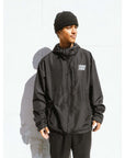 Man wearing The Stacked Jacket Black, a 10k lightweight and weatherproof shell jacket for snowboarding, with adjustable hood and zippable pockets.