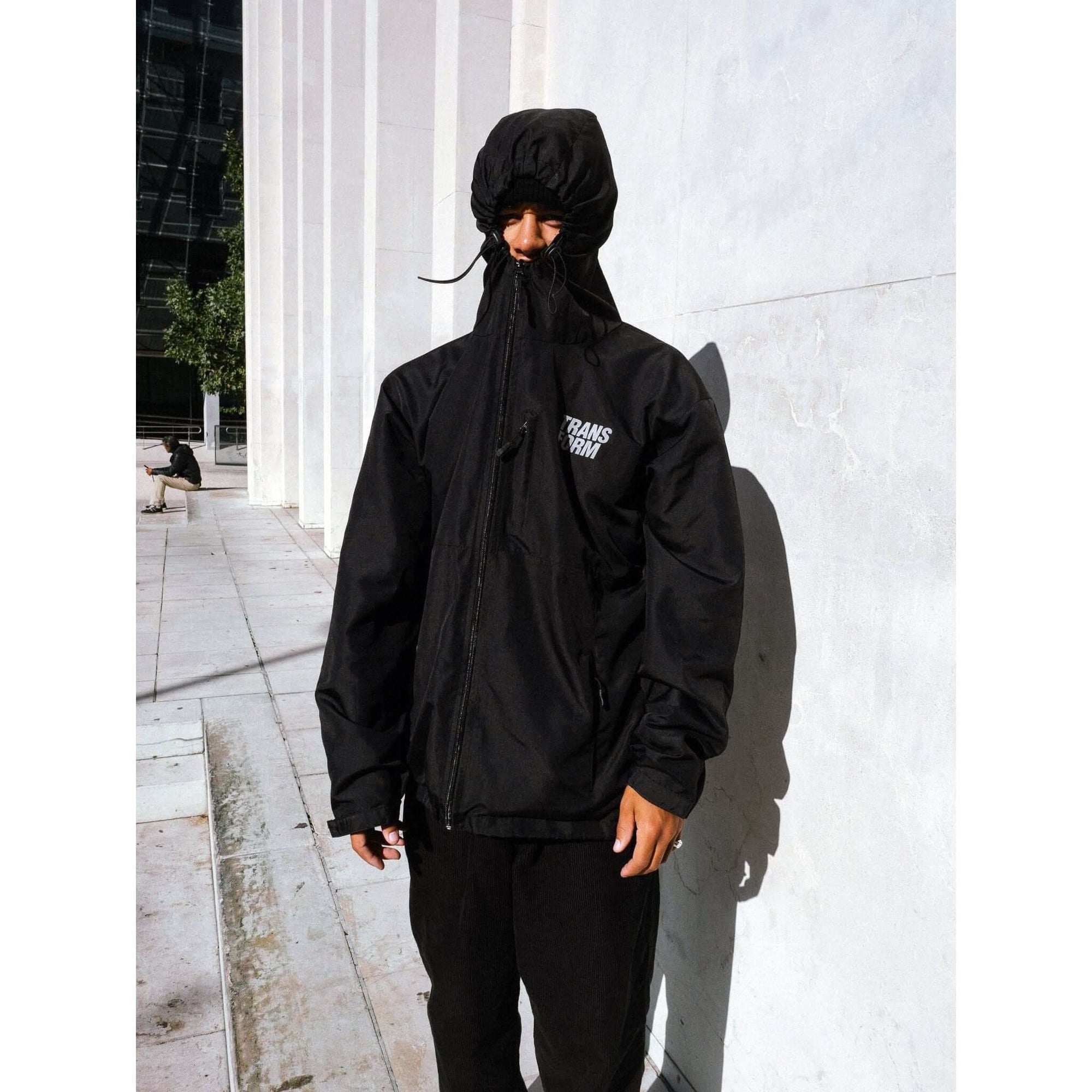 Man wearing The Stacked Jacket Black with hood up, showcasing snowboarding shell jacket for winter, waterproof and weatherproof.